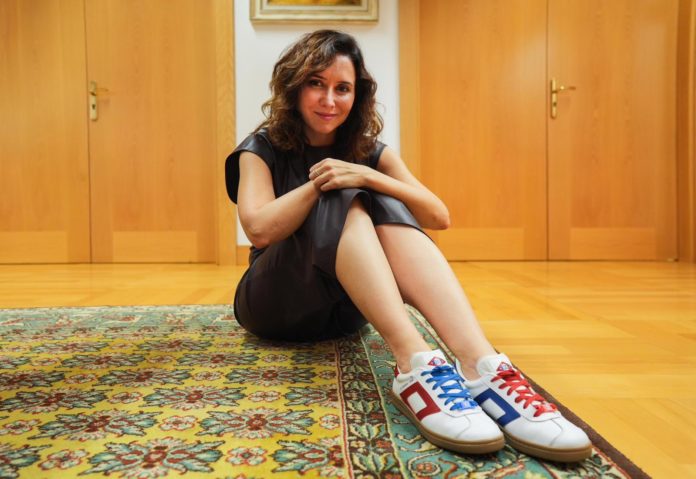 La presidenta de la Comunidad de Madrid, Isabel Díaz Ayuso, posa con unas zapatillas deportivas diseñadas con el Metro de Madrid como principal motivo