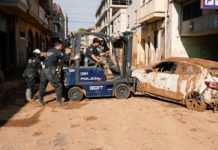 Policías nacionales retiran un vehículo en una calle llena de fango en Paiporta