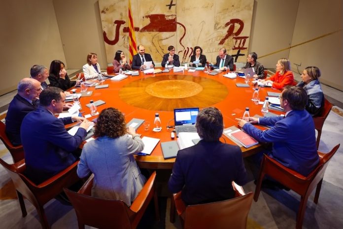 El presidente Salvador Illa y sus consellers reunidos durante el Consell Executiu celebrado este lunes. Todos ellos están sentados alrededor de una gran mesa redonda de color caoba.