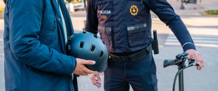 Un policía junto a un hombre que tiene en sus manos un casco para circular en bicicleta o patinete